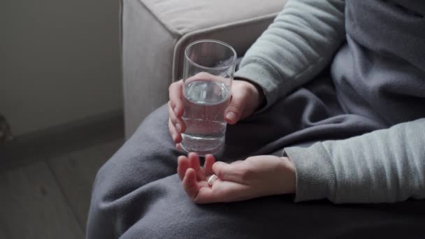 Το κορίτσι κρατάει ένα ποτήρι νερό και ένα χάπι στα χέρια της. Λήψη φαρμάκων. — Αρχείο Βίντεο