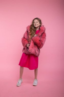 Moda kıyafetleri içinde kız manken stüdyoda pembe arka planda açık pembe kürk manto. Biçim.