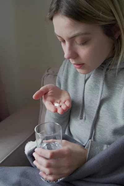 Mujeres jóvenes enfermas tomando pastillas mientras están sentadas en el sofá en casa — Foto de Stock