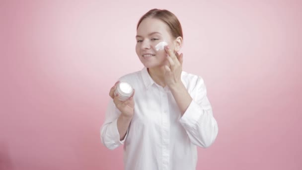 Natuurlijke witte moisturizer op de wang van een mooi meisje. — Stockvideo