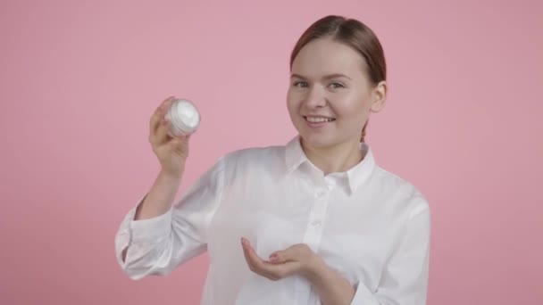 La chica sostiene una crema en sus manos y la prueba con su mano — Vídeos de Stock