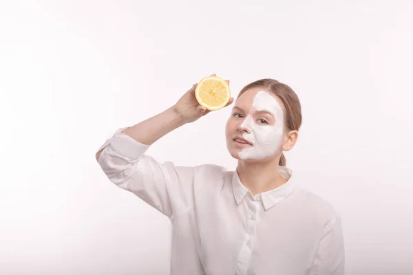 Mädchen auf weißem Hintergrund mit Maske im Gesicht. In der Hand der Orangenfrucht. — Stockfoto