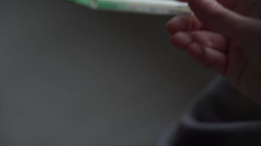 Battaniyeye sarılı bir kız cıvalı termometrenin sıcaklığını düşürüyor. Orvi, koronovirüs, akut solunum hastalığı belirtileri..