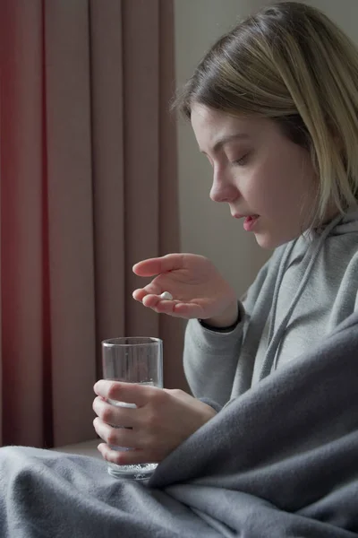 Vista da vicino della donna che tiene in mano le pillole e prende un bicchiere d'acqua — Foto Stock