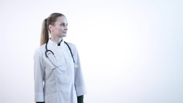 Ein schönes junges Mädchen, eine Klinikmitarbeiterin zeigt ihre Hand nach rechts. Kopierraum. — Stockvideo