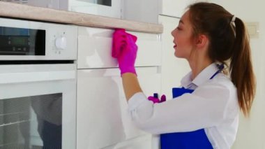 Odayı temizlemek, beyaz yüzeyi pembe eldivenler ve pembe bir bezle silmek. Rujlu esmer kız temizlik yapıyor..