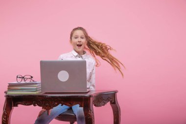 Laptopun yanında ağzı açık, uzun sarı saçlı güzel bir genç kız..