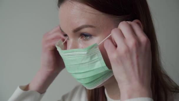 Güzel genç kız özel olarak nasıl tıbbi maske takılacağını gösteriyor. Orvi, koronovirüs, grip. — Stok video