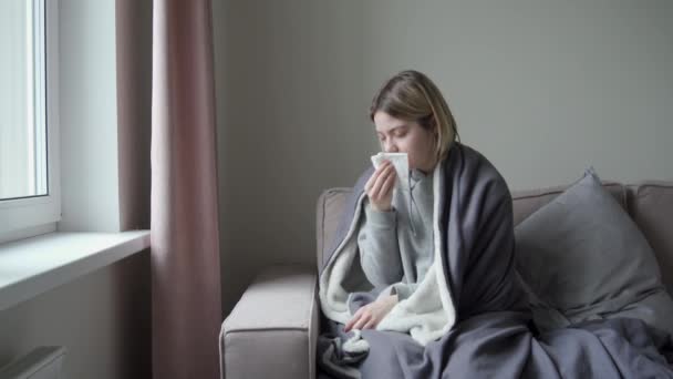 Egy fáradt szemű lány ül a tetővel szemben. Beteg és kifújja az orrát. Orvi tünetei, coronavirus influenza, allergia, sinusitis. — Stock videók