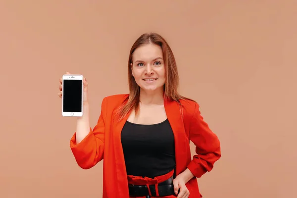 Una chica en ropa brillante con un smatphone en sus manos . — Foto de Stock