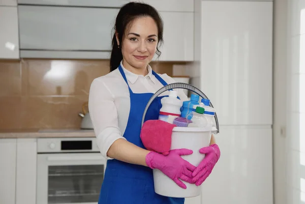 Ragazze con un secchio in mano. Secchio di detergenti. Sullo sfondo di una bella cucina moderna bianca . — Foto Stock