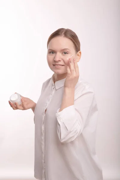 Junge schöne Mädchen bekommt natürliche weiße Creme auf dem Gesicht. — Stockfoto