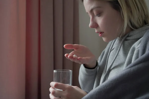 Ill meisje met medicijnen en een glas handen in haar handen.. — Stockfoto