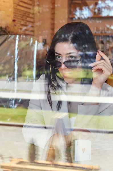 Фото модной, современной, стильной женщины через стекло кафе . — стоковое фото