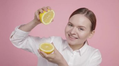 Genç bir kız iki büyük sarı limon dilimini elinde tutuyor..