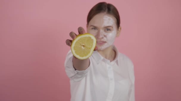 Primer plano exprimiendo jugo natural. Chica con crema en la cara . — Vídeo de stock