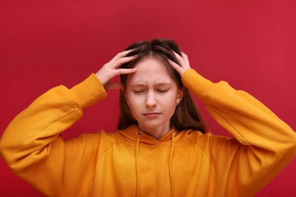 Una ragazza ha mal di testa. Una foto brillante. La ragazza si aggrappa alla testa . — Foto Stock