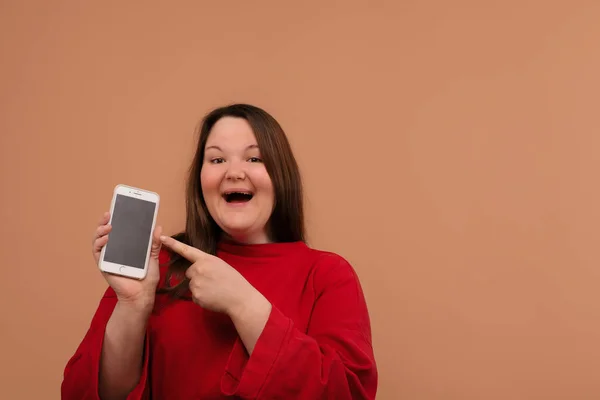 Una chica sonriente señala su mano a la pantalla en blanco de su teléfono . — Foto de Stock