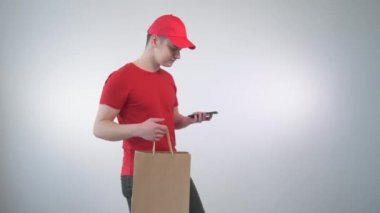 Genç adam kurye, müşteriyle telefonda konuşuyor ve adresi belirtiyor..