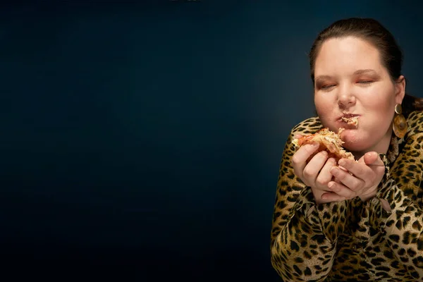Tlustá holka v leopardí blůze s hamburgerem v ruce. Prázdné místo nalevo. Světlý make-up. — Stock fotografie