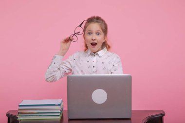 Kızın bir fikri var. Genç bir kız dizüstü bilgisayarda beyaz gömlek ve siyah çerçeveli gözlüklerle oturuyor..