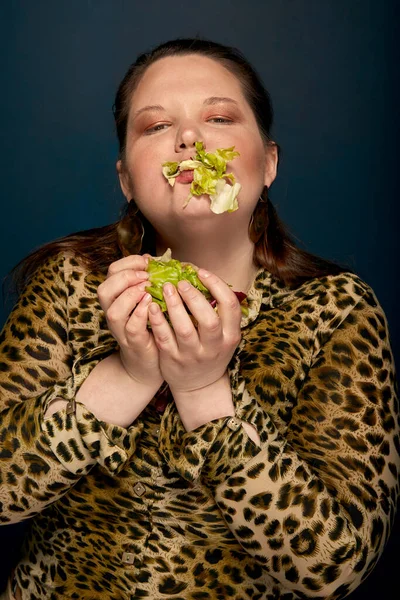 Fet tjej äter sallad, grönsaker. Leopardavtryck. Vänster kopieringsutrymme. Foto i ateljén. — Stockfoto