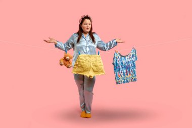 Mavi pijamalı şişman bir kız kollarını geniş elbiselerinin yanına açıyor..