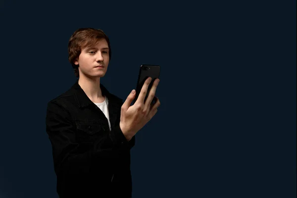 Хлопець із зачіскою дивиться на мобільний телефон . — стокове фото