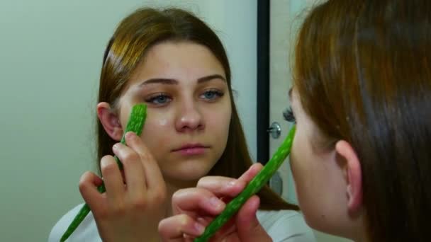 Frau blickt in Spiegel und verwendet Aloe-Vera-Blatt auf Wange — Stockvideo