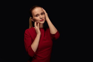 Güzel, güzel bir kadın ellerini yüzüne koyup poz veriyor.