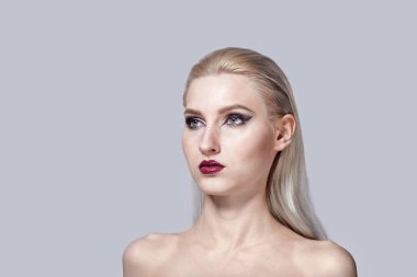 Açık tenli, doğal saçlı güzel bir kız yana bakıyor. Parlak makyaj.