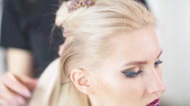 Kuaförde parlak makyajlı bir kız. Kuaför saçını yapıyor..