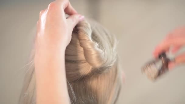 Une coiffeuse fait une coupe de cheveux à une fille blonde . — Video
