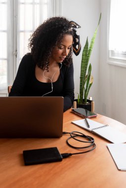 Laptop ve belgelerle evde çalışan genç Latin kadının fotoğrafı.
