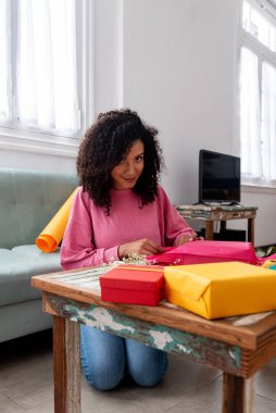 Latin kadın el yapımı el yapımı hediyeleri evdeki masada paketliyor.