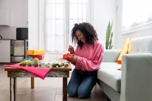 Mujer latina envolviendo regalos artesanales hechos a mano en la mesa en casa — Foto de Stock