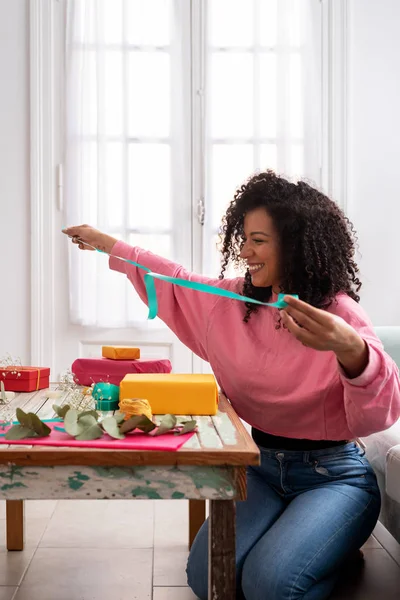 Mujer latina envolviendo regalos artesanales hechos a mano en la mesa en casa — Foto de Stock