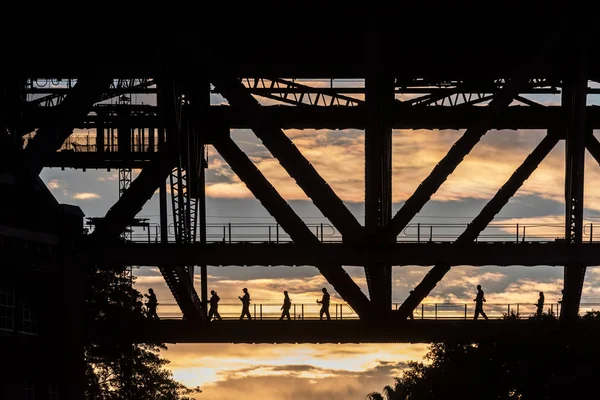सूर्यास्त पर सिडनी हार्बर ब्रिज के पार चलने वाले लोगों का सिल्हूट — स्टॉक फ़ोटो, इमेज