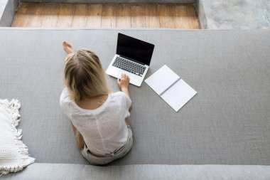 Kanepede dizüstü bilgisayar kullanan bir kız.