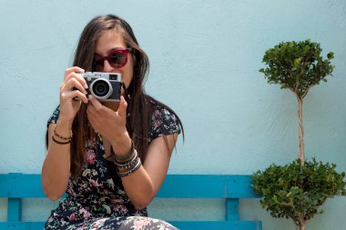 Dışarıda güneş gözlüklü bir kadın Cholula, Meksika 'da elinde retro kamerayla fotoğraf çekiyor.