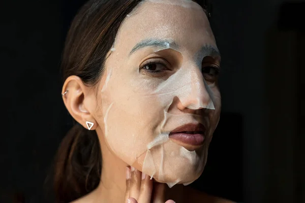 Μελαχρινή γυναίκα με ένα φύλλο ενυδατική μάσκα στο πρόσωπό της — Φωτογραφία Αρχείου