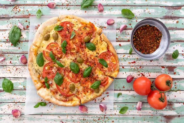 Freshly made wood fired pizza viewed from above on rustic turquoise boards