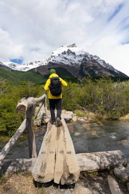 Patagonya, Arjantin 'de bir yürüyüş gününde tahta bir köprüden geçen bir dağcı.