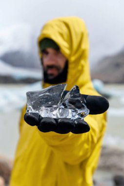 Laguna Torre, Chalten, Arjantin 'de kocaman bir buz parçası tutan bir adam. 