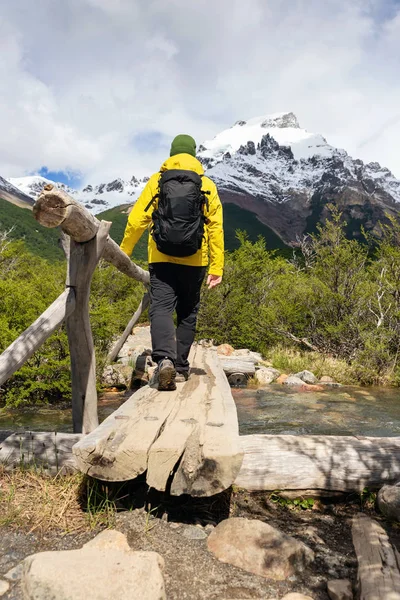 Egy hegymászó, aki átsétál egy fahídon egy kiránduló napon az argentin Patagóniában. — Stock Fotó