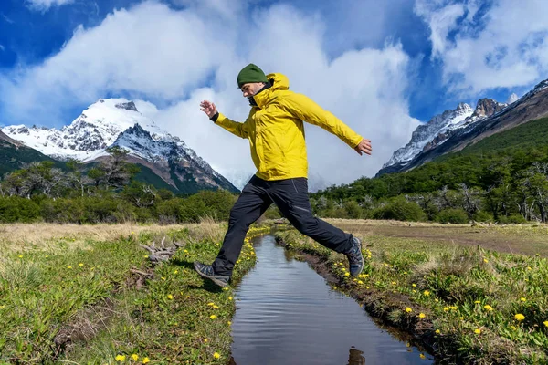 Horolezec skákající přes řeku v den trekking v El Chalten, Patagonia, Argentina — Stock fotografie
