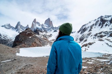 Arjantin, Patagonya 'daki Fitz Roy Dağı' nın eteğinde mavi ceketli bir yürüyüşçü kadın.