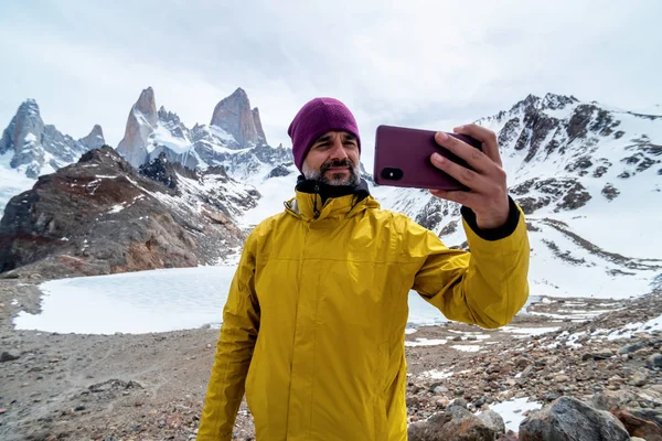 A hiker with a yellow jacket taking a photo on the base of Fitz Roy Mountain in Patagonia, Argentina — Fotografia de Stock