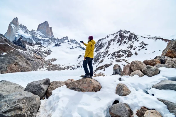 Un excursionista con una chaqueta amarilla tomando una foto sobre la base de Fitz Roy Mountain en Patagonia, Argentina. — Foto de Stock