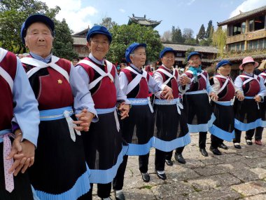 16 Mart 2019: Sokakta geleneksel Naxi etnik grubu kostümüyle dans eden kadınlar. Lijiang, Çin